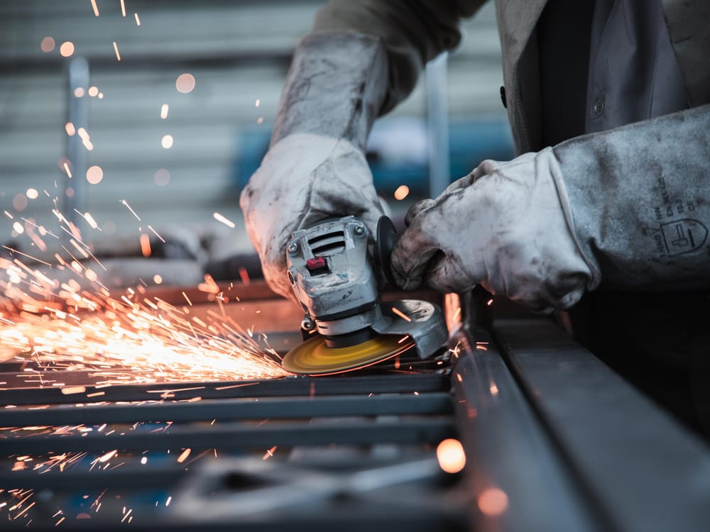 Metalworker grinding steel with sparks flying